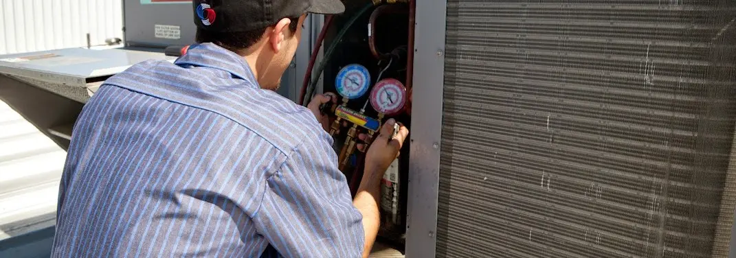 HVAC technician servicing a condenser unit in Goshen